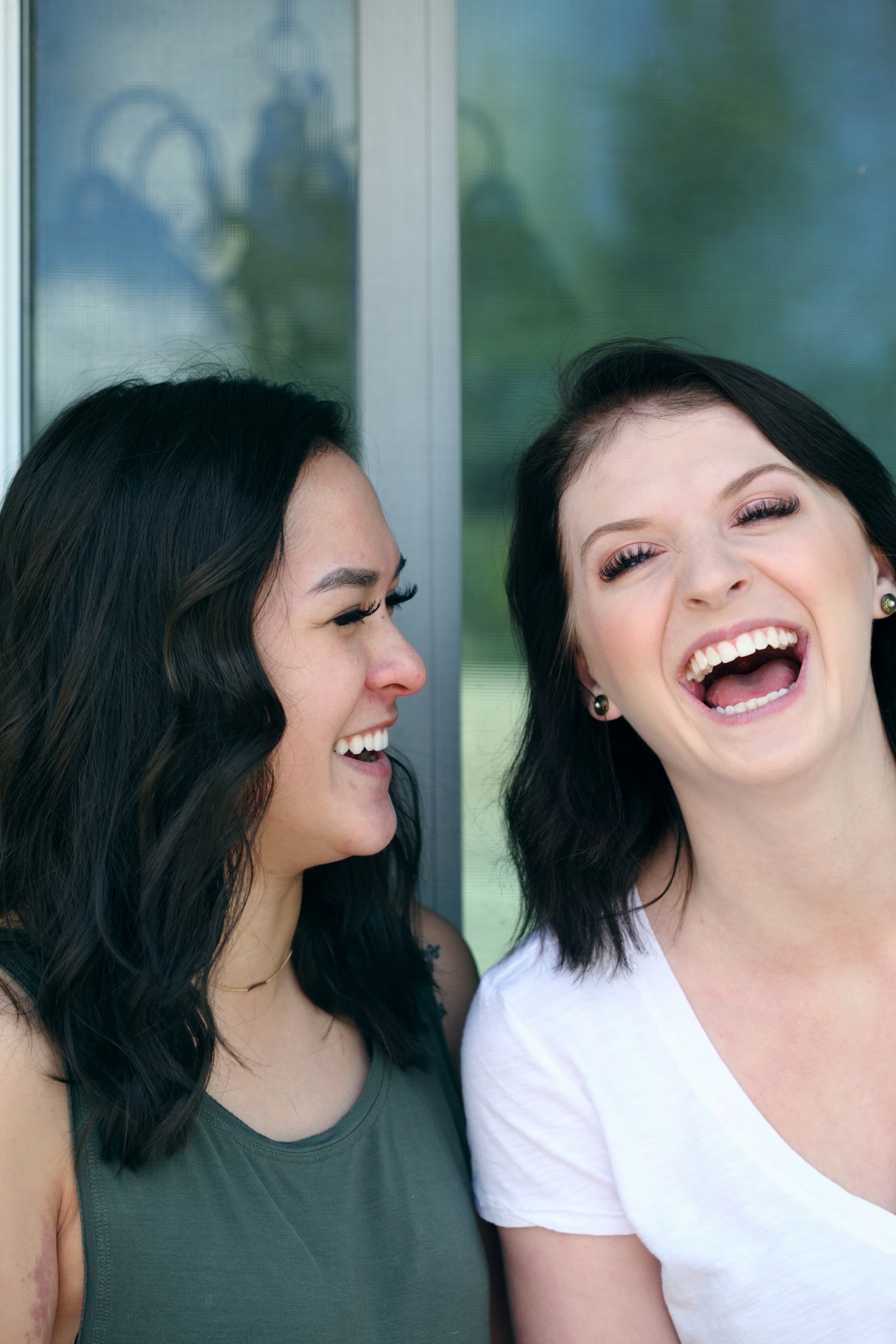 Two women laughing together during a warm, genuine conversation on a couch