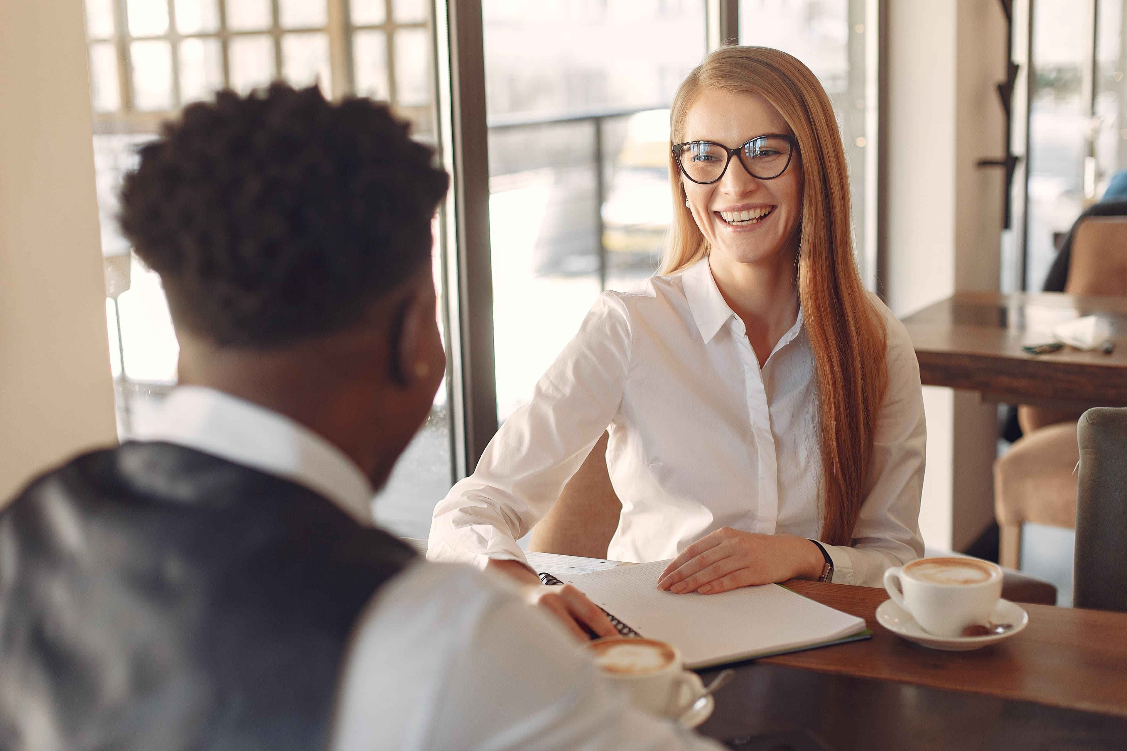 Two people sitting together at a table, smiling and having a warm, genuine conversation over coffee