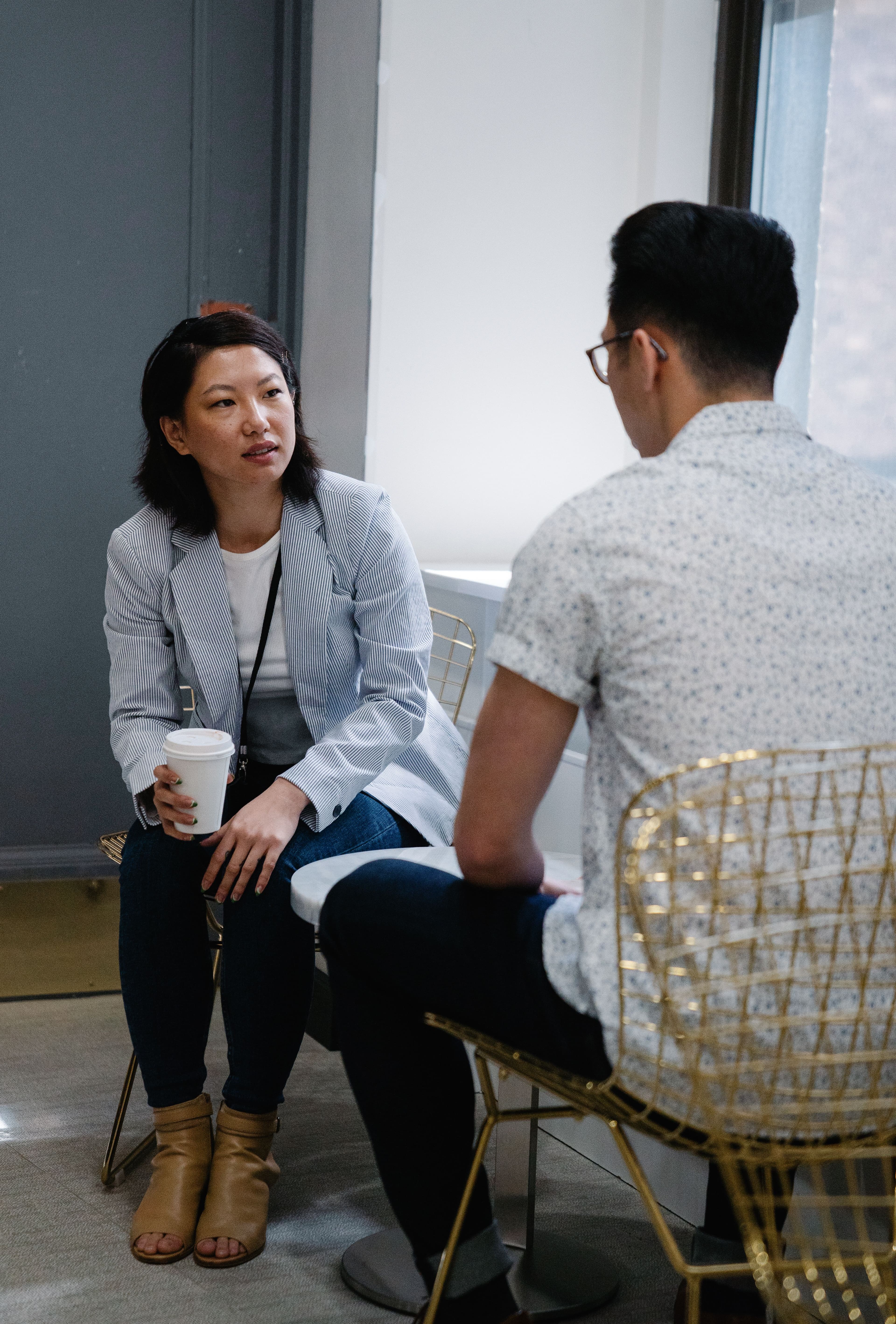 Two people sitting across from each other at a small cafe table, mid-conversation over coffee